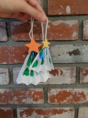 Folded Christmas Tree Ornament - hand holding the ornaments with fireplace bricks in the background