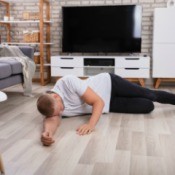 A man who has fainted on a living room floor.