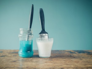 Two paint brushes soaking in water.