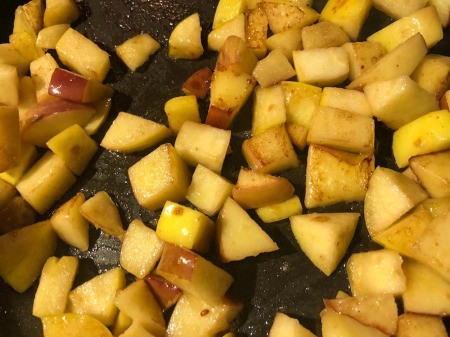 adding apple pieces to pan