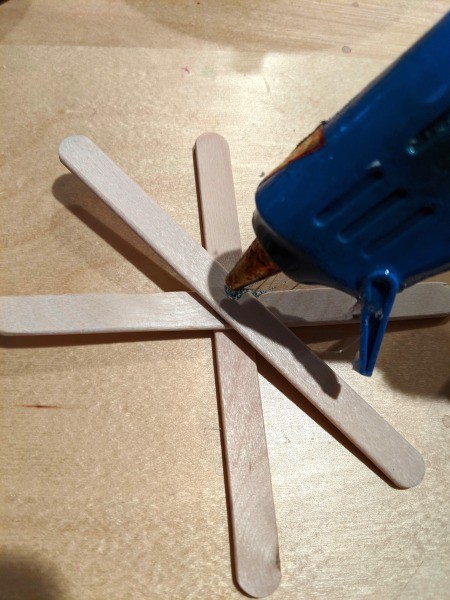 Making Popsicle Stick Snowflake Ornaments - third stick in place and more glue being added