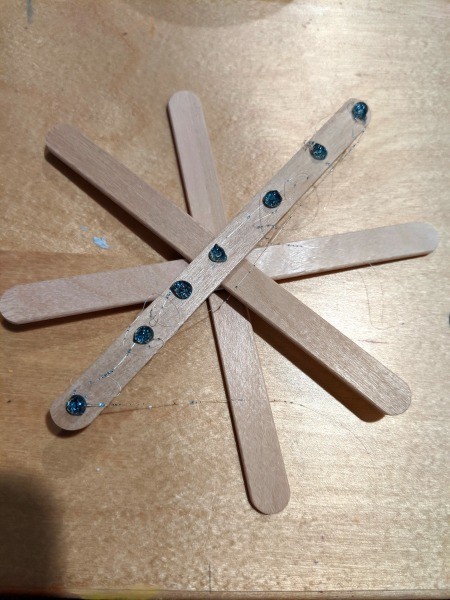 Making Popsicle Stick Snowflake Ornaments - blue glue dots on top stick