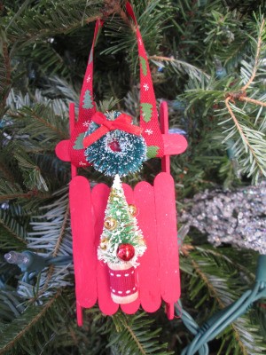 Popsicle Stick Sled - red sled with wreath and tree decorations, hanging on the Christmas tree