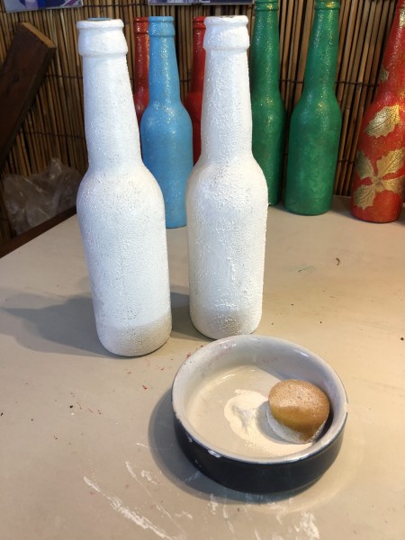 Recycled Bottle Holly Leaf Candlestick Holder - two bottles with a dish containing white paint and a small sponge for applying