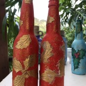 Recycled Bottle Gold Leaf Candlestick Holders - two red bottles with gold leaf elements