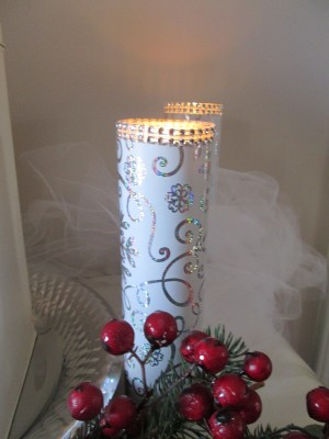 An inexpensive candle that has been decorated with wrapping paper and gems.