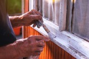 A senior man painting a windowsill.