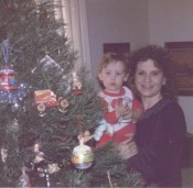 A mother and son next to a Christmas tree.