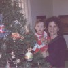 A mother and son next to a Christmas tree.