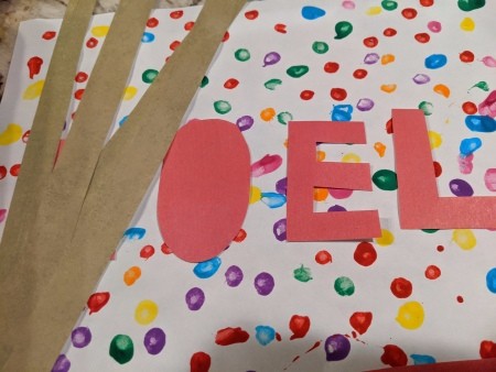 Noel Q-Tip Painting  - brown paper border and red paper letters cut out