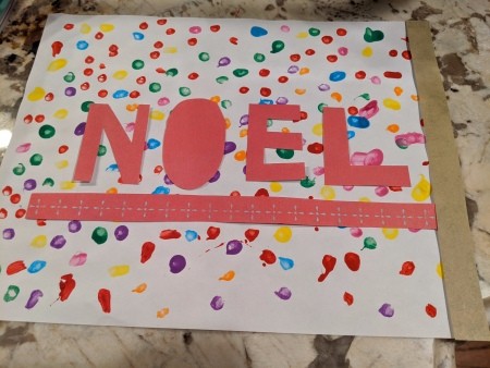 Noel Q-Tip Painting - letters with a underscore of pink paper and one piece of the border in place