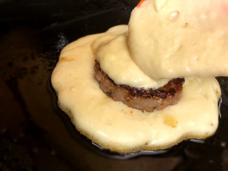 more batter on top of Sausage on cooking pancake