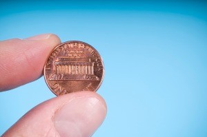 A finger and thumb pinching a penny.