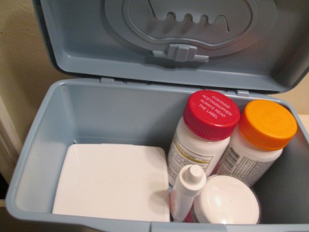 Medicine and supplies inside a baby wipe container.