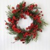 A wreath made from greenery and red berries.