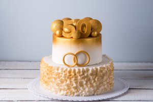 Two tiered cake with wedding rings and a 50 on top.