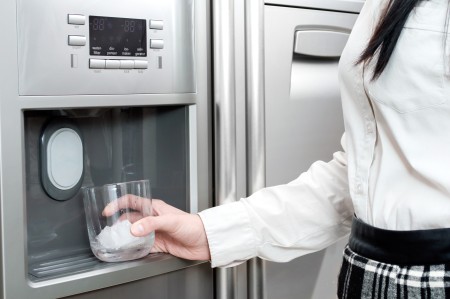Woman getting ice from fridge.