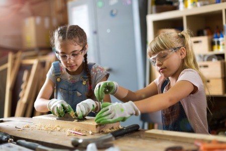 Two young girls working on a craft project with wood.