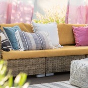 Colorful curtains behind a rattan couch with many pillows.