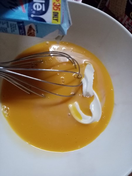 adding milk to whisking egg yolk