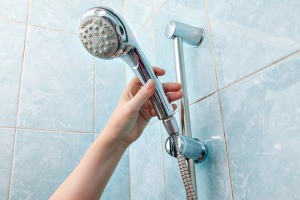 A hand grabbing a handheld showerhead.