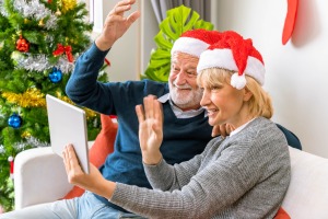 A couple waving at a tablet screen at Christmastime.