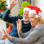 A couple waving at a tablet screen at Christmastime.