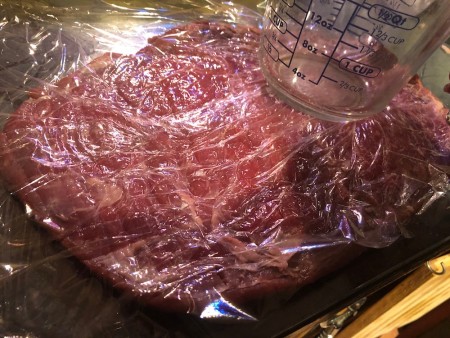 steak covered with wrap to flatten