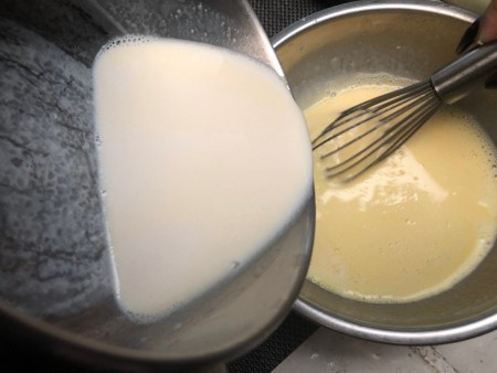 pouring heated milk into egg