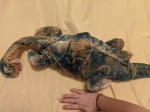A toy stuffed dinosaur on a wood surface.