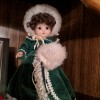 Identifying a Porcelain Doll - doll wearing a dark green velvet coat and hat with white trim and matching muff