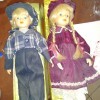 Identifying Porcelain Dolls - boy doll in jeans and plaid shirt and girl with braids and a lace trimmed dress with pantaloons.