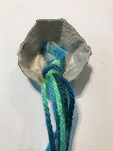 Making an Egg Carton Octopus - tape or glue the yarn bundle to the inside of the carton section