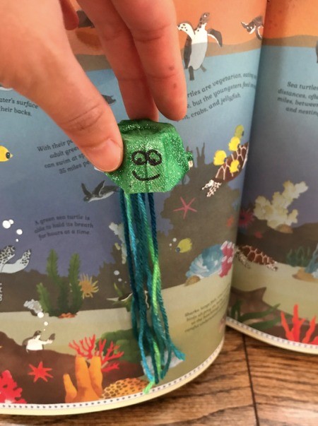 Making an Egg Carton Octopus - octopus with face drawn on being held in front of the book
