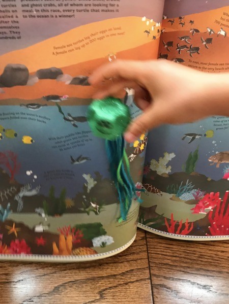 Making an Egg Carton Octopus  - child moving the octopus in front of a standing book