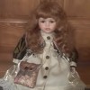Identifying a Porcelain Doll  - sitting doll wearing a brown and cream satin coat carrying a brocade shoulder bag