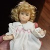 Identifying a Porcelain Doll - small blonde doll wearing a long white nightgown with pink smocking