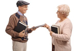 Two older people exchanging books.