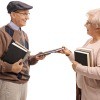 Two older people exchanging books.