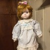 Value of a Heritage Porcelain Doll - red haired doll wearing a lace trimmed light blue dress and pantaloons