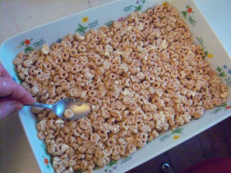 pressing Cheerio Peanut Butter treats into pan