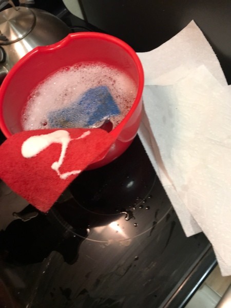 A bowl and scrubby pads for cleaning a stovetop hood.