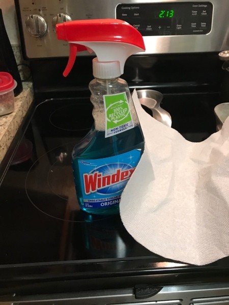 A bottle of Windex on top of a stove.