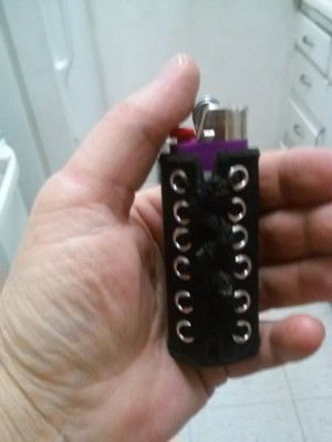 A lighter in a cover that is made with eyelets.