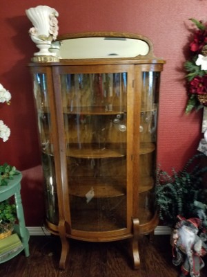 Value of a Curio Cabinet - a perhaps antique curio cabinet with curved glass front and sides and an oval mirror on top