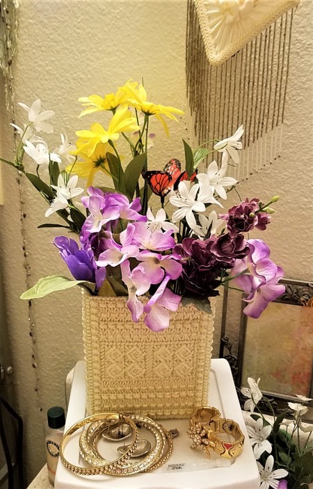 A tissue holder upside down to hold flowers.