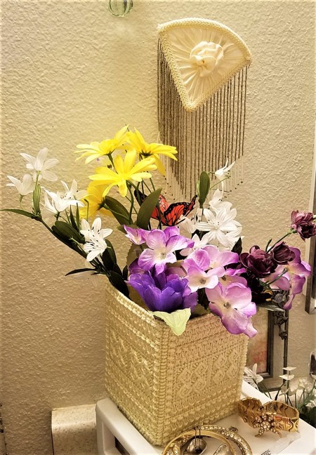 A tissue holder upside down to hold flowers.