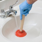 A plunger being used in a bathroom sink.