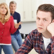 A young man looking irritated with his parents, who are also frustrated.
