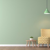 A green wall with a yellow striped chair in front of it.